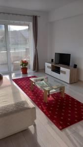 - un salon avec un tapis rouge et une table en verre dans l'établissement Piatra Craiului Residence Zărnești, à Zărneşti