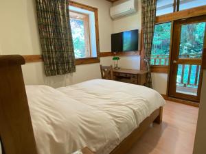 a bedroom with a bed and a flat screen tv at Taoyuan Villa B&B in Puli