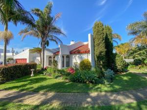 a white house with palm trees and a lawn at Bollinger Guest House in George
