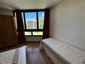 een slaapkamer met een bed en een groot raam bij Résidence Grande Masse - 2 Pièces pour 5 Personnes 894 in Les Menuires
