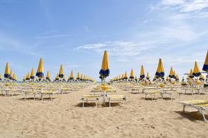 een groep stoelen en parasols op een strand bij Piazza Marconi Attico Duplex per 5 persone in Lido di Jesolo