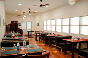 un comedor con mesas, sillas y ventanas en Marari Beach Palace, en Mararikulam