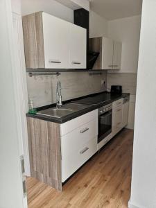 una cucina con mobili bianchi e un lavandino di Ferienwohnung Villa Portugal a Leinsweiler Altre 4 foto