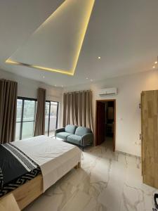 - une chambre avec un grand lit et un canapé dans l'établissement Résidence ADJIBADE, à Cotonou