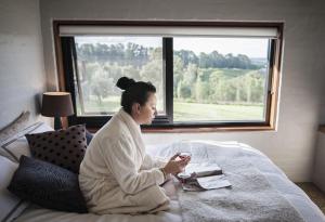 a woman sitting on a bed with a glass of wine at Borrodell Vineyard in Orange