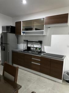 La cuisine est équipée d'armoires en bois et d'un réfrigérateur en acier inoxydable. dans l'établissement Departamento en nuevo altata, à Altata