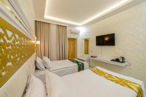 ein Hotelzimmer mit 2 Betten und einem TV in der Unterkunft Arslan Boutique Hotel in Xiva