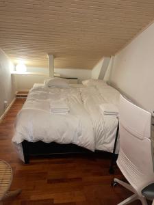 1 dormitorio con 1 cama blanca grande y 1 silla en Idyllinen puutaloasunto en Vaasa