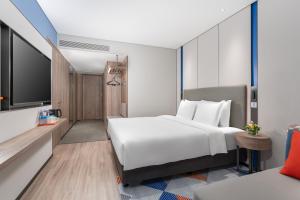 um quarto de hotel com uma cama branca e uma televisão em Holiday Inn Express Guangzhou Panyu Dashi, an IHG Hotel em Guangzhou