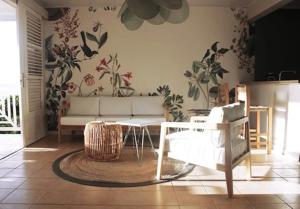 a living room with a white couch and flowers on the wall at Villa vue de rêve mer & forêt primaire in Les Trois-Îlets