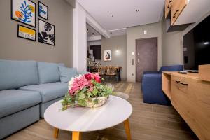 - un salon avec un canapé et une table fleurie dans l'établissement Pelagio apart 2 by homebrain, à Alexandroúpolis