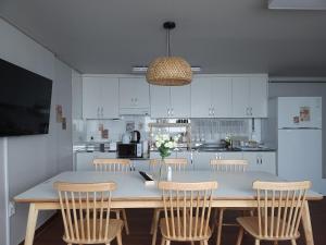 a kitchen with a large table with chairs and a kitchen with white cabinets at Happy Jumunjin House in Gangneung