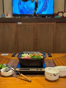 una sartén de comida sentada sobre una mesa en 源泉掛け流し付き貸切別荘-Authentic private home with Private Kusatsu Onsen - THE HIDEOUT VILLA KUSATSU- en Kusatsu