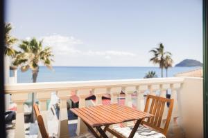 a wooden table and chairs on a balcony with the ocean at Manthos Beachfront Apartments in Laganas