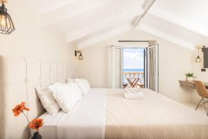 a white bedroom with a large bed with a view of the ocean at Manthos Beachfront Apartments in Laganas
