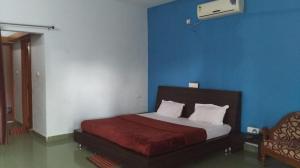 a bedroom with a bed and a blue wall at Vamoose Rupmati The Valley Hotel in Māndu
