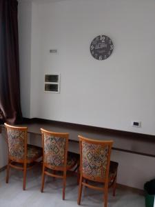 坎特洛的住宿－Hotel motel residence Gonzaga，一张桌子,上面有四把椅子和墙上的时钟