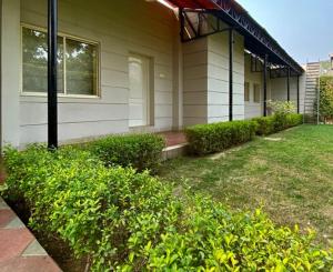 uma casa com arbustos verdes em frente em Status Club Resort em Kanpur