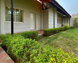 a house with green bushes in front of it at Status Club Resort in Kānpur