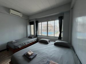 2 Betten in einem Zimmer mit Fenster in der Unterkunft norndee hostel in Aranyaprathet