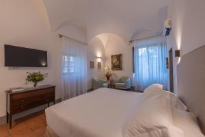 a bedroom with a large white bed and a tv at Corte Di Valle in Greve in Chianti