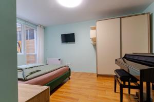 a bedroom with a bed and a desk and a piano at Mirela Guest Apartment in Veliko Tŭrnovo