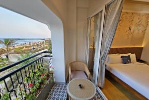 a bedroom with a bed and a balcony with a view of the ocean at Sea Gadabout - Seaside Stays in Puducherry