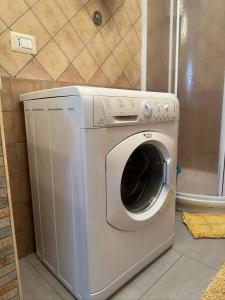 uma máquina de lavar roupa na casa de banho ao lado de um WC em Appartamento La Petrosa em Nova Siri