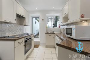 a kitchen with white cabinets and a microwave at Sam Bs in Brixham