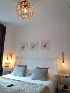 een slaapkamer met een wit bed en een kroonluchter bij Be Cottage Hotel in Le Touquet-Paris-Plage