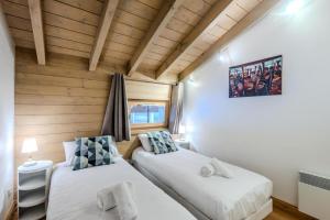 2 Betten in einem kleinen Zimmer mit Holzwänden in der Unterkunft Résidence Les Balcons Des Bois Venants Bat A - Pièces 444 in Morzine