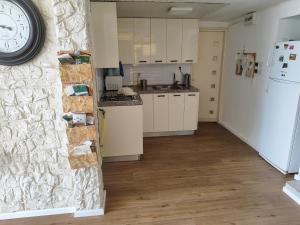 a kitchen with white cabinets and a clock on a wall at Adi in Arad
