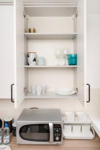 uma cozinha com um micro-ondas num armário branco em Atlas Arena Green Studio em Lódź