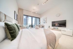 a white bedroom with a large bed and a tv at Burj Khalifa Poolside, Canal Boardwalk, Parking in Dubai