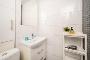 a white bathroom with a sink and a mirror at Atlas Arena Green Studio in Łódź