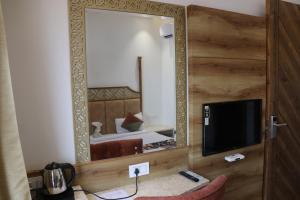 a mirror in a room with a bed and a television at HOTEL RV GOLDEN in Amritsar