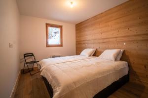 um quarto com uma cama grande e uma parede de madeira em Résidence LUMI BATIMENT B - Appartement LUMI B pour 5 Personnes 024 em Valmorel