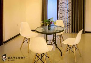 a dining room table with white chairs and a table with wine glasses at Bay Surf Monkey Villa 05 Double Rooms with 05 Pvt Bathrooms With AC & 2 kitchens in Weligama