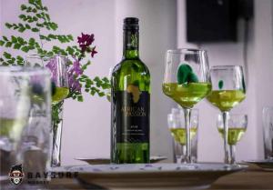 a bottle of wine sitting on a table with two glasses at Bay Surf Monkey Villa 05 Double Rooms with 05 Pvt Bathrooms With AC & 2 kitchens in Weligama