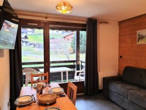 ein Wohnzimmer mit einem Tisch und einem großen Fenster in der Unterkunft Residence La Corniche - Studio pour 4 Personnes 154 in Morzine