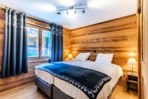 - une chambre avec un lit et un mur en bois dans l'établissement Chalet La Passionata - Chalets pour 8 Personnes 154, à Morzine
