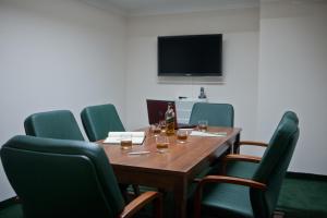 a conference room with a wooden table and green chairs at Hotel Masovia in Giżycko