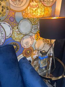 a wall covered in plates and a table with a lamp at Versace The Malt House in Burton upon Trent