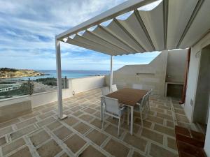 een patio met een tafel en stoelen en de oceaan bij Borea Luxury Home in Otranto