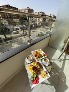 カイロにあるKhattab Pyramids View Hotelのバルコニーにテーブルと2皿の食べ物