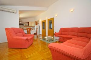una sala de estar con 2 sillas rojas y una mesa. en Hella Apartments, en Trogir