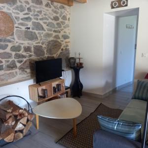 a living room with a table and a stone wall at Les maisons d'Ustou. in Ustou