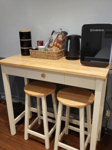 a wooden table with two stools and a microwave at Dragonflies in Hordle