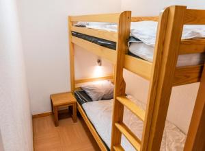 a room with three bunk beds and a table at Résidence Le Parc Des Airelles - 2 Pièces pour 6 Personnes 301 in Les Orres
