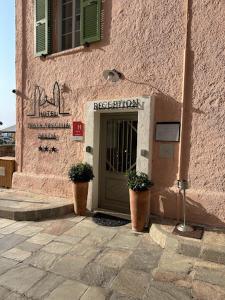 un bâtiment avec une porte et deux usines devant lui dans l'établissement Hôtel Posta Vecchia, à Bastia